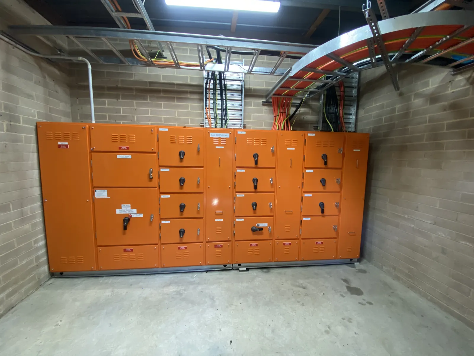 Industrial switchboard installation with orange electrical cabinets